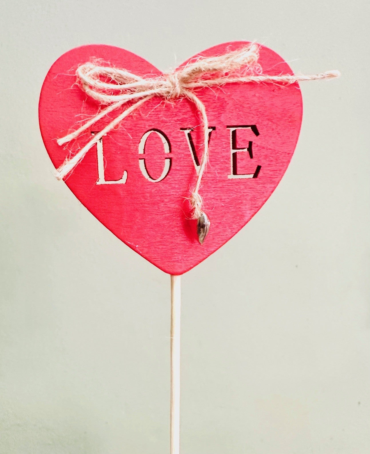 Red wooden heart pick with cut-out 'LOVE' text and twine bow, gift decoration