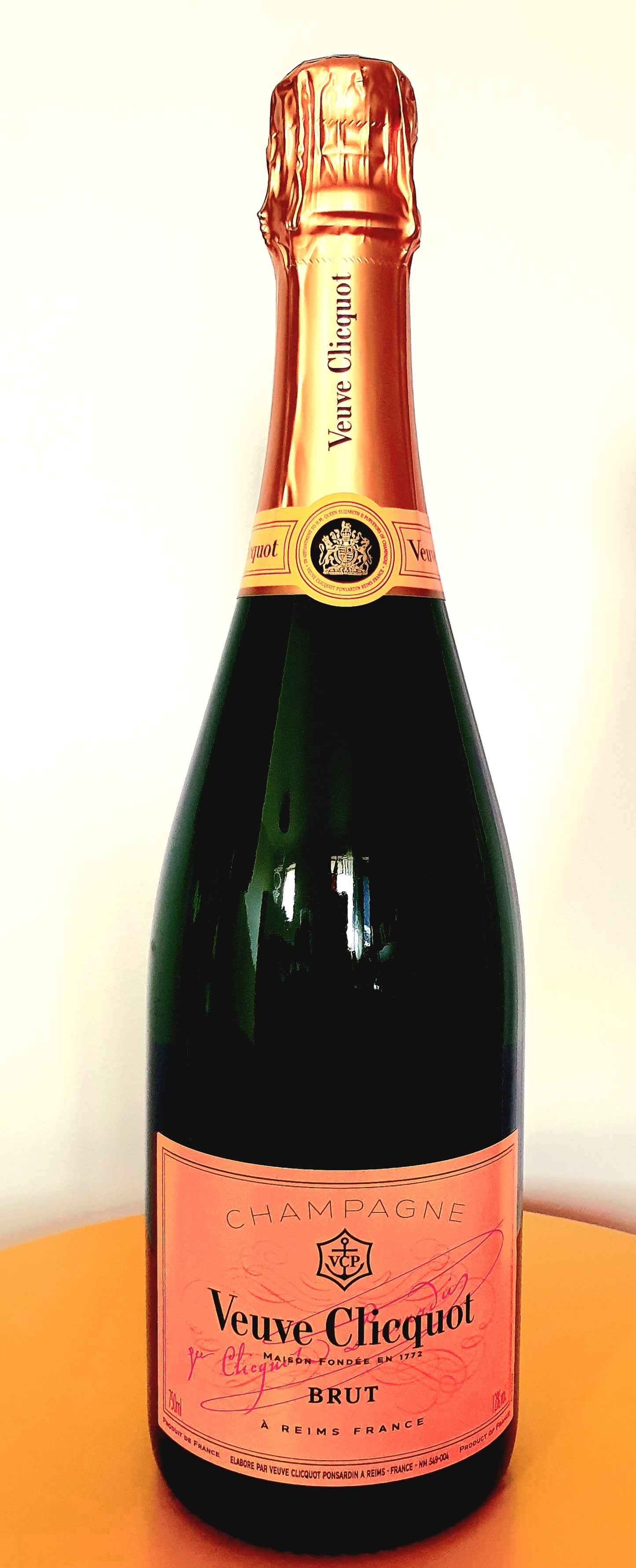 Veuve Clicquot Brut Champagne bottle with orange foil and label on a light background