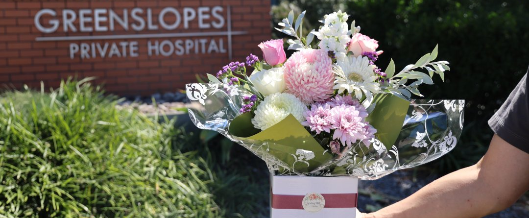 Spring Hill Florist posy box arrangement held outside Greenslopes Private Hospital Brisbane — same-day flower delivery Greenslopes Brisbane