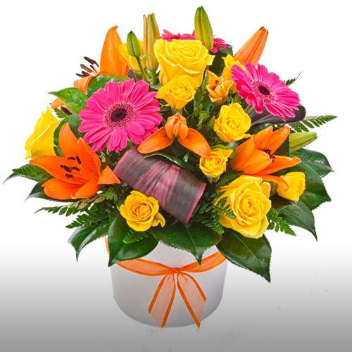 Bright bouquet of orange lilies, pink gerberas, yellow roses and greenery in a white hatbox