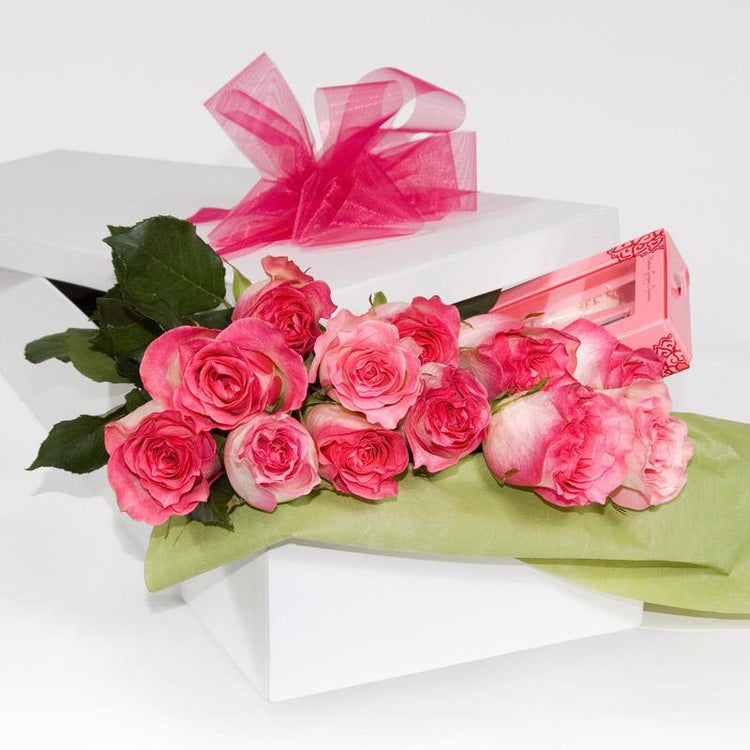 Bouquet of pink roses with green leaves in white gift box with pink ribbon, elegant flower delivery