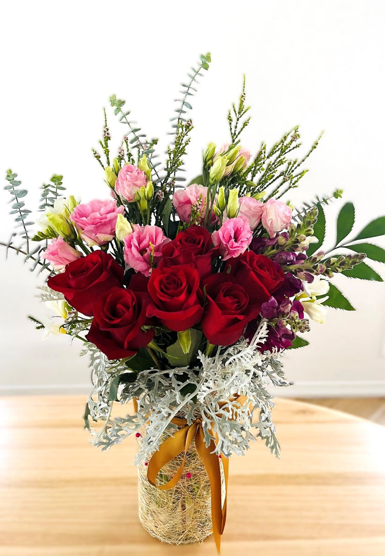 Rustic vase with native flowers, including protea, lilies, eucalyptus, and yellow accents