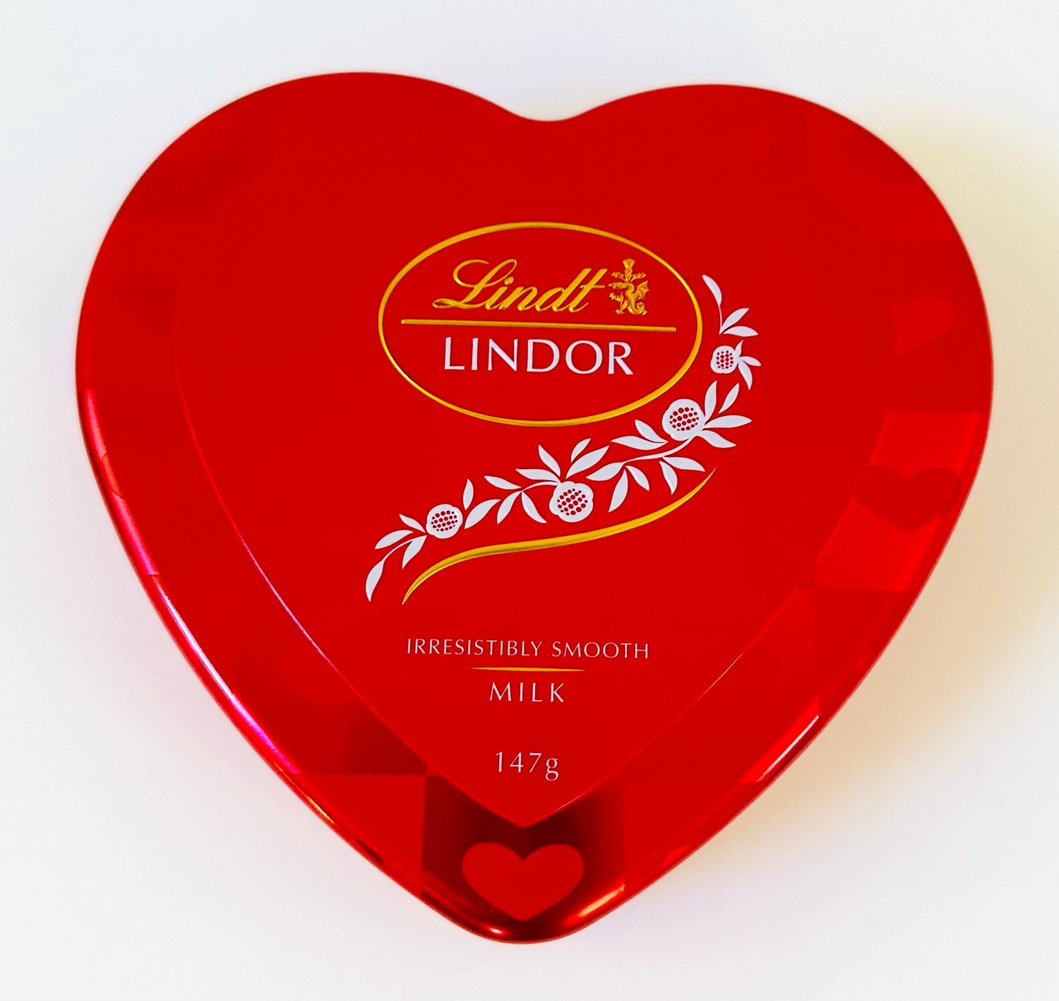 Red heart-shaped Lindt Lindor milk chocolate gift box, 147g, with floral design on lid.
