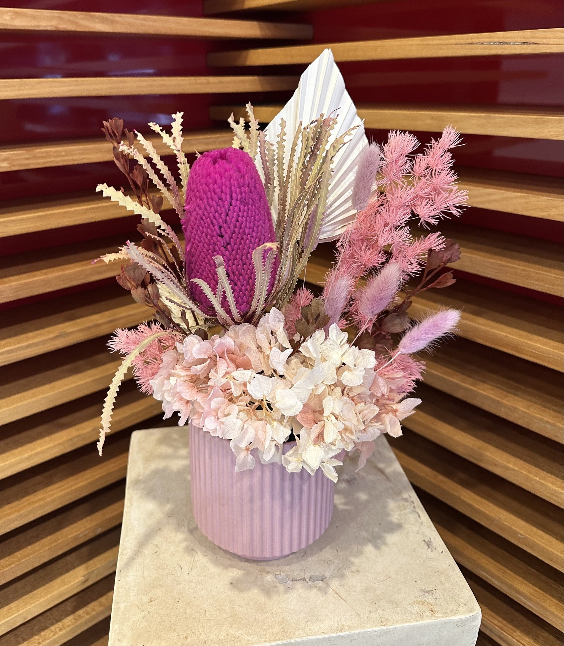 Pink and white dried flower arrangement in a ribbed vase, featuring native blooms.
