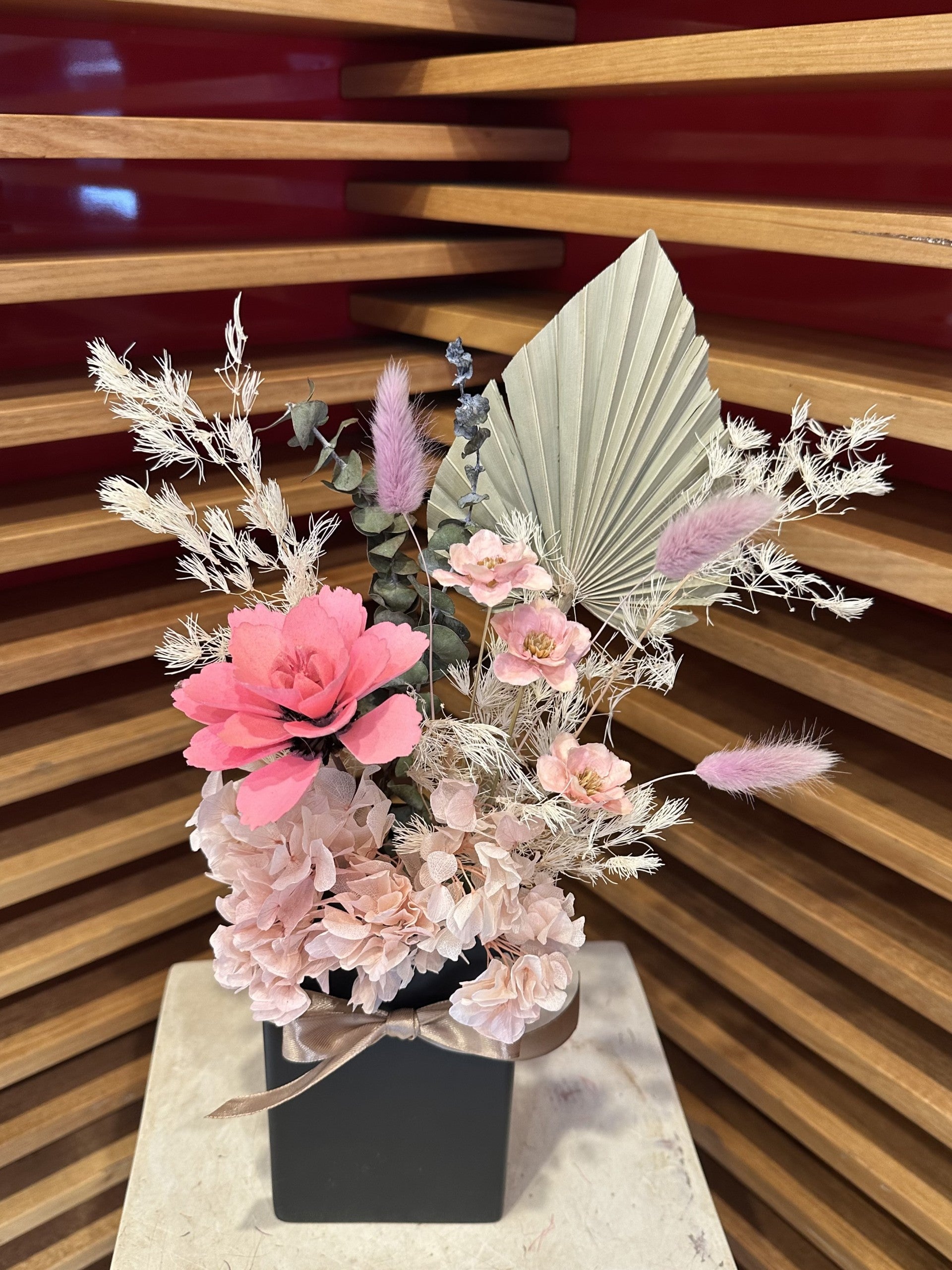 Elegant dried flower arrangement with pink and beige blooms in a black gift box.