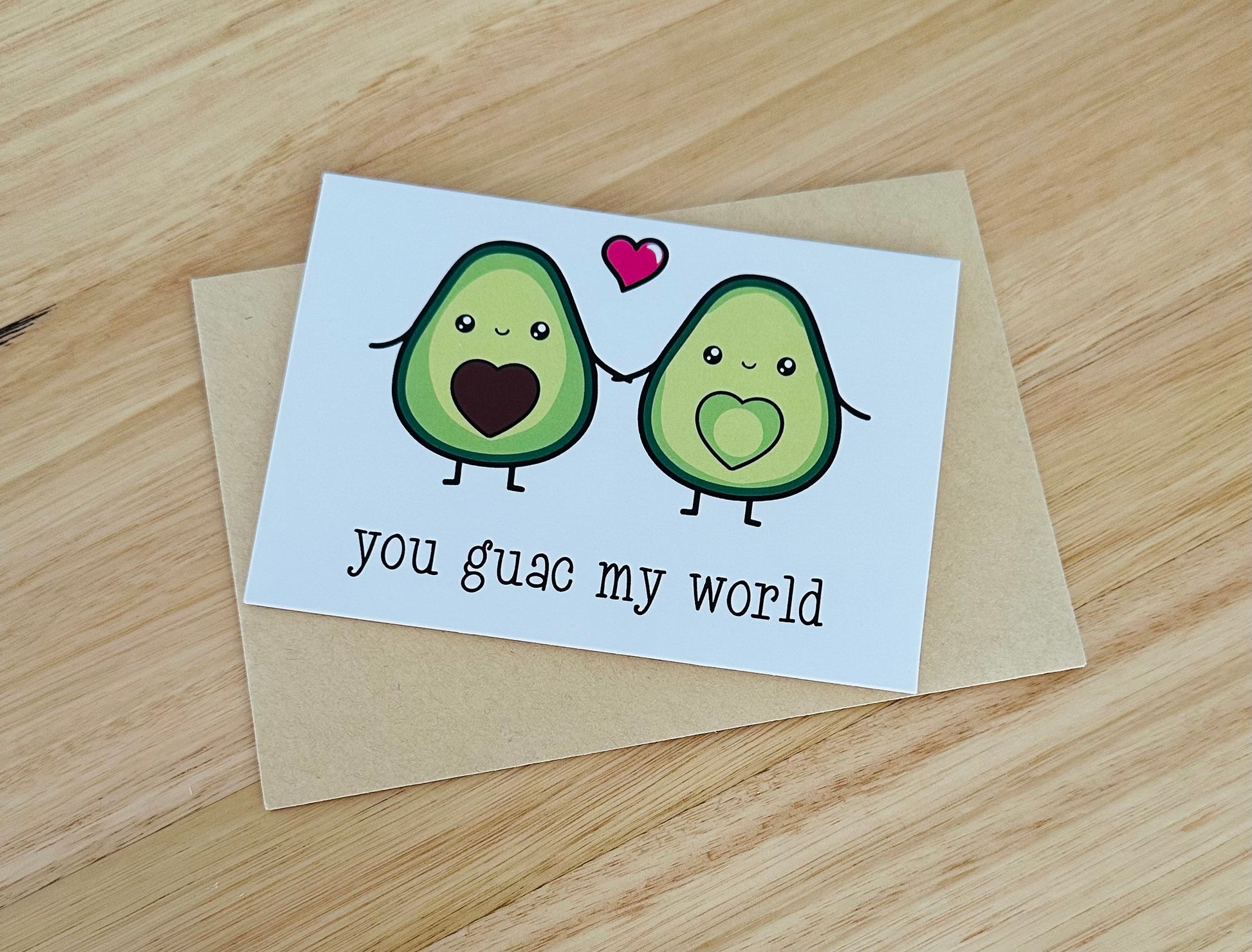 Cute avocado pun greeting card with two smiling avocados, hearts, and 'you guac my world' text