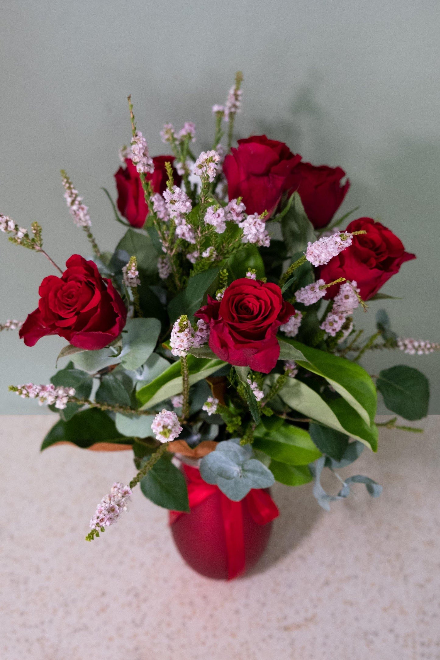 Red rose and pink flower bouquet in red vase, ideal for romantic or special occasion gift.