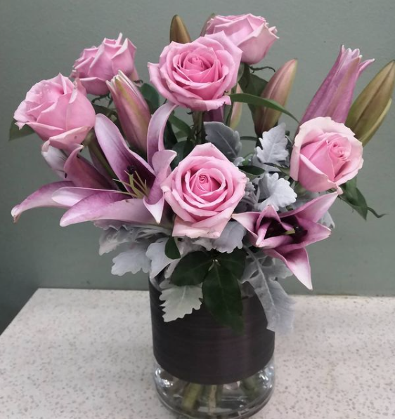 Pink roses and lilies floral arrangement in a vase with foliage